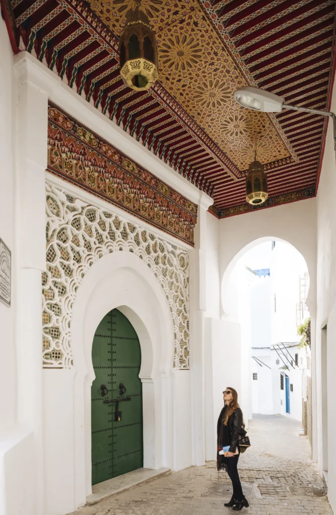 Entrée d’un riad marocain avec porte traditionnelle et plafond décoré en bois sculpté
